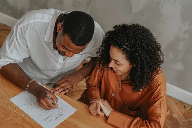 A couple signing an adoption certificate at a table, viewed from above. Five permission records for UGC marketplaces audience research in England