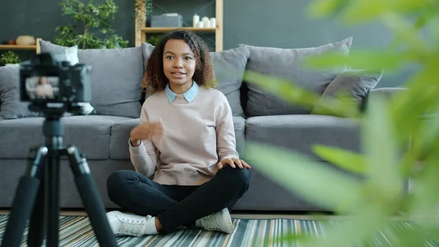 A young woman creates content for her vlog at home, sitting in front of a camera. UGC marketplaces hidden costs: six packages beyond the quote