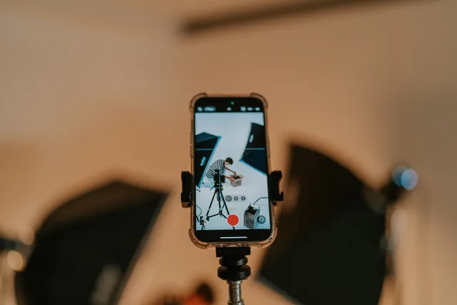 Close-up of a smartphone on a tripod capturing a photo shoot in a studio setting. UGC marketplaces key metrics: asset evidence measures