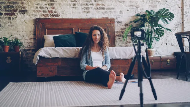 Woman seated in bedroom with camera, creating content in relaxed environment. The UGC marketplace entry checklist, from authority and briefs to age uncertainty and exit