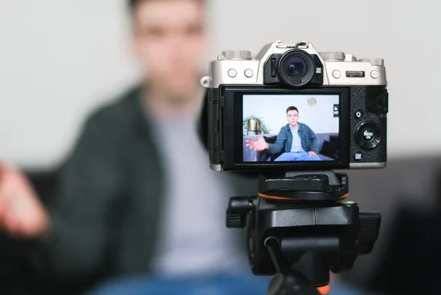 Man recording a vlog indoors using a mirrorless camera on a tripod with selective focus. UGC marketplaces strategy: buyer-owned evidence checks