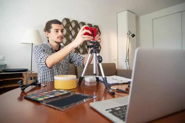 A male vlogger adjusts his camera on a tripod, preparing for a video shoot in a stylish home studio. UGC marketplaces tools and providers: a vetting method